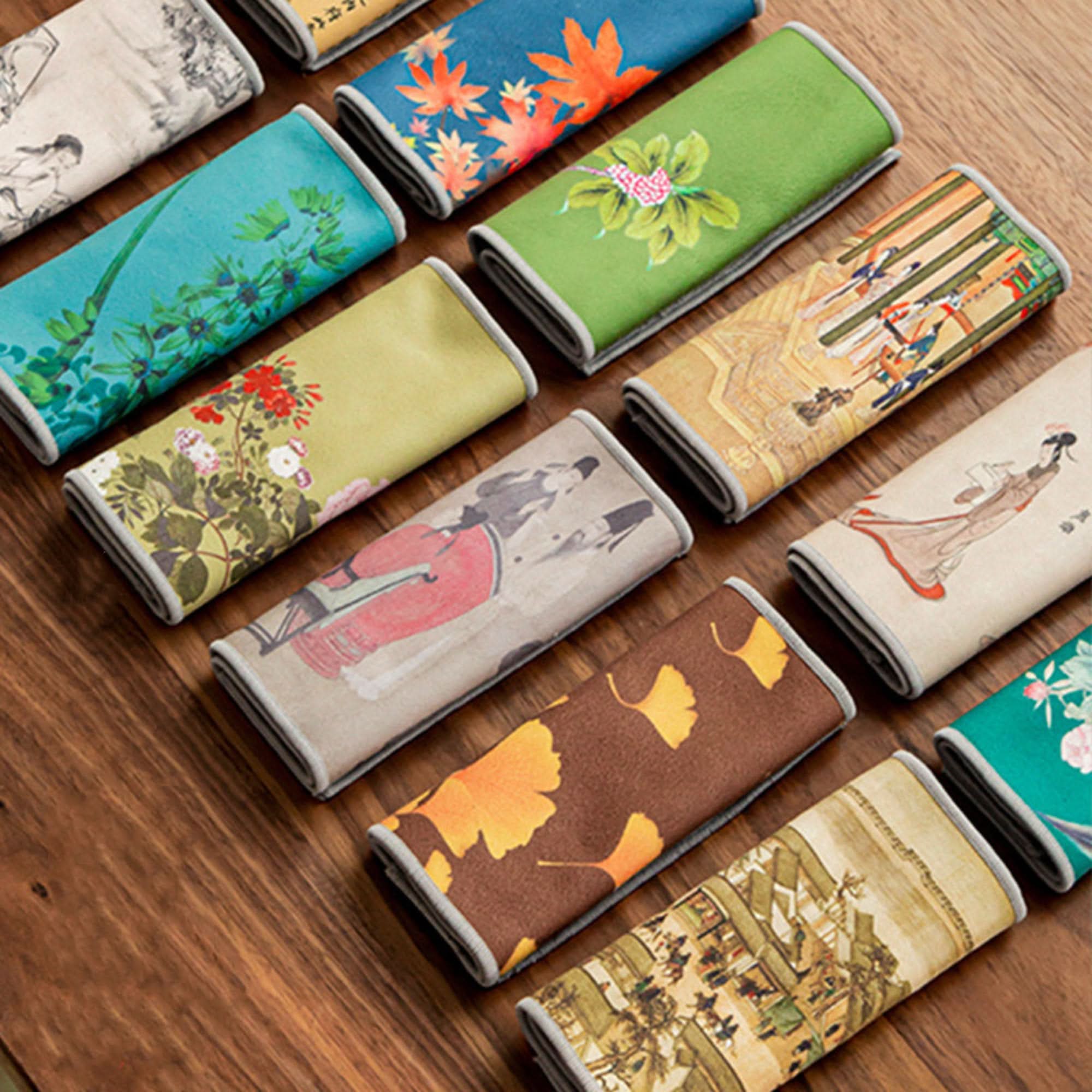 Japanese tea towels in Ukiyo-e style featuring floral and scenic prints on a wooden surface.